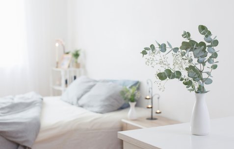 eucalyptus-and-gypsophila-in-vase-in-white-bedroom-with-gold-accents-in-background